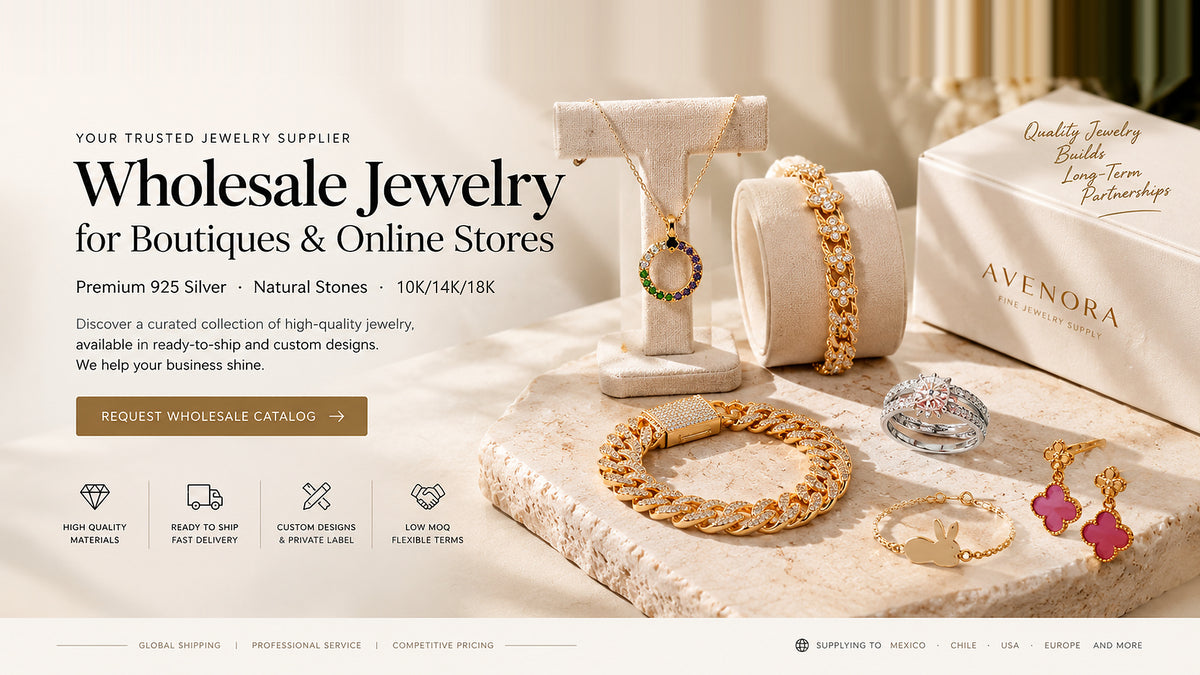 Avenora Atelier fine jewelry wholesale collection featuring gold Cuban link bracelet, gemstone circle pendant necklace, floral chain bracelet, diamond rings, and four-leaf clover drop earrings displayed on travertine stone.